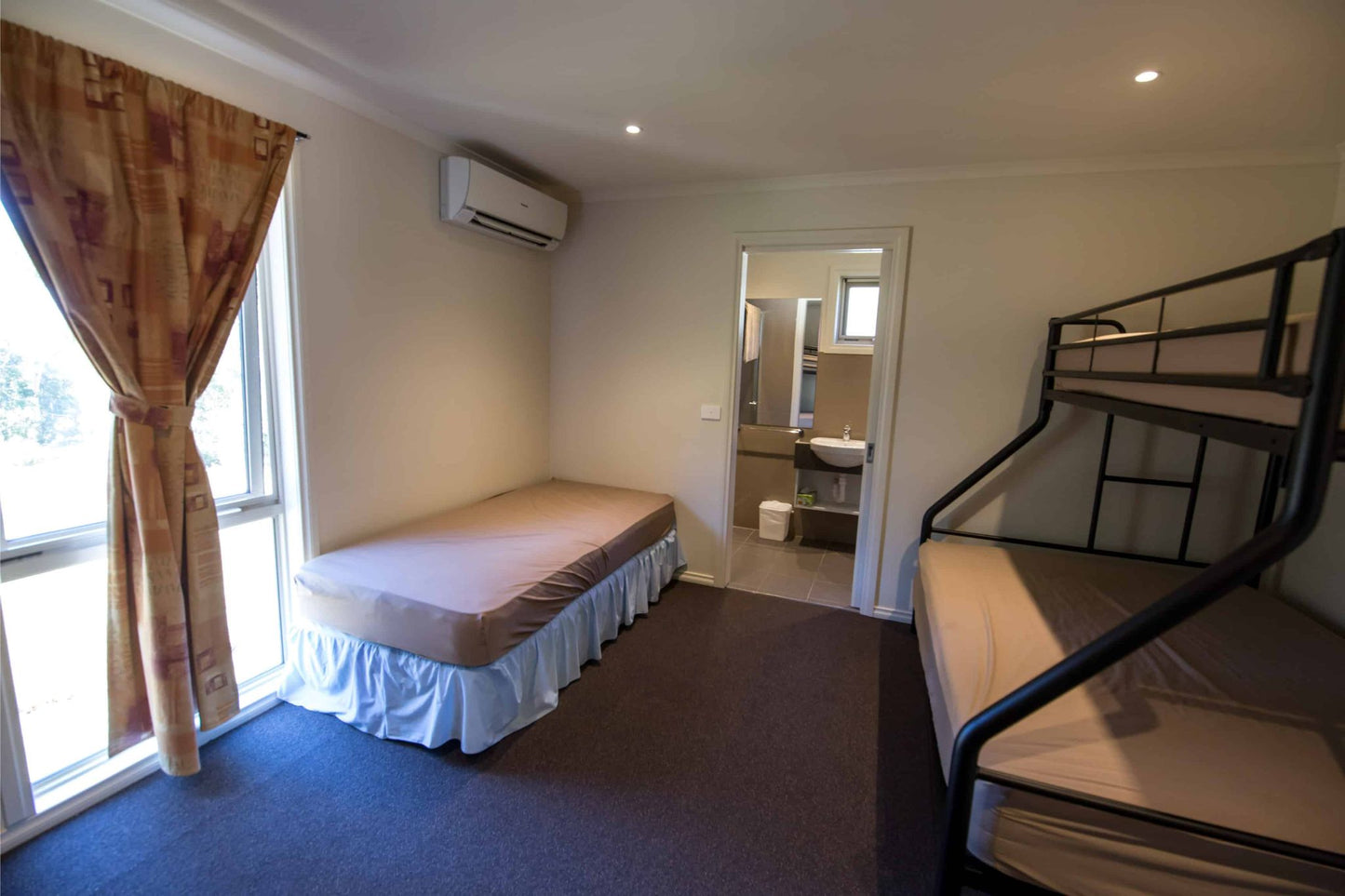 Retreat bedroom showing double bed, bunk beds and ensuite access at Lyrebird Park camp accommodation Victoria