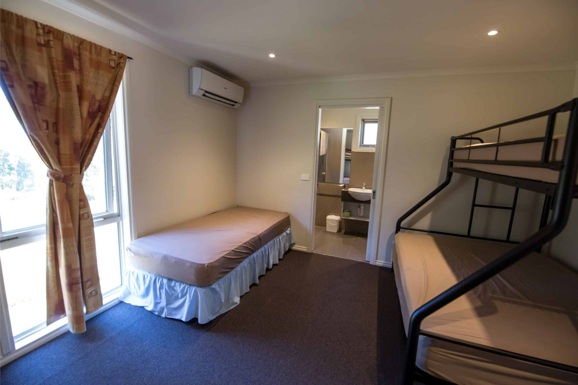 Retreat bedroom showing double bed, bunk beds and ensuite access at Lyrebird Park camp accommodation Victoria