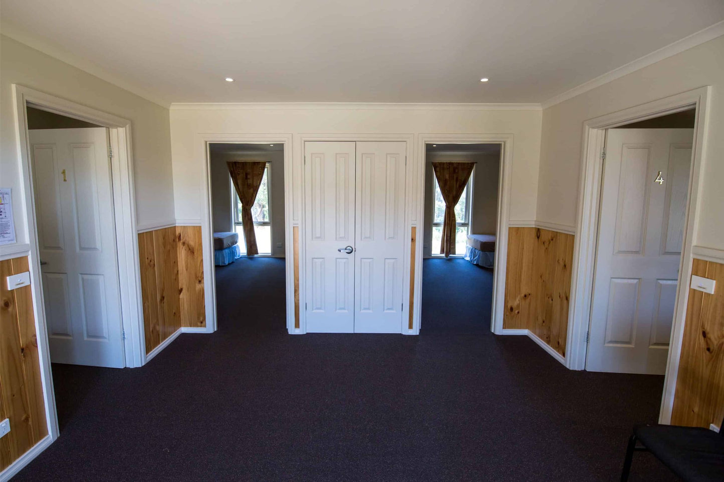 Interior hallway of accommodation cabin showing multiple bedroom doors at Lyrebird Park retreat centre