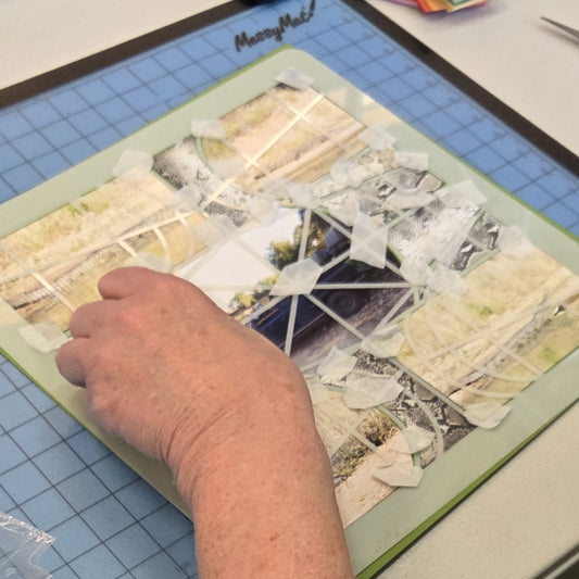 Crafter's hands creating a scrapbook layout using a layout stencil and tape at a craft event in Morwell