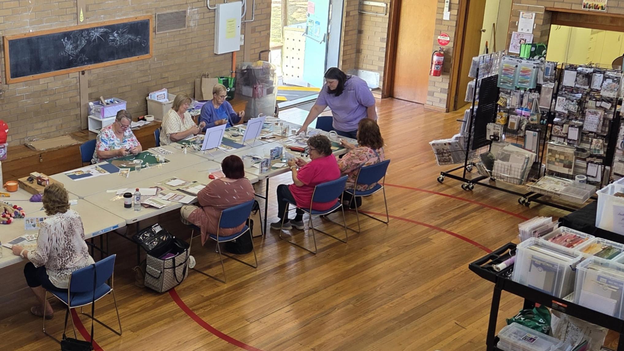 Overhead view of Julie teaching crafters at tables in bright, spacious venue at Handmade Haven craft event in Morwell Victoria