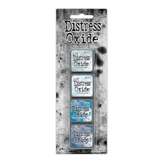 Packaged set of four Ranger Distress Oxide Mini Ink Pads from Kit 10 in Speckled Egg, Tumbled Glass, Mermaid Lagoon and Faded Jeans, shown in original Tim Holtz packaging with grungy black-and-white background.
