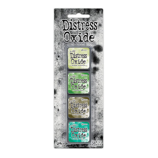 Packaged set of four Ranger Distress Oxide Mini Ink Pads from Kit 15 in Shabby Shutters, Mowed Lawn, Forest Moss and Lucky Clover, shown in original Tim Holtz packaging with grungy black-and-white background.
