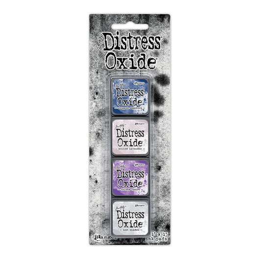 Packaged set of four Ranger Distress Oxide Mini Ink Pads from Kit 17 in Chipped Sapphire, Milled Lavender, Wilted Violet and Lost Shadow, shown in original Tim Holtz packaging with grungy black-and-white background.

