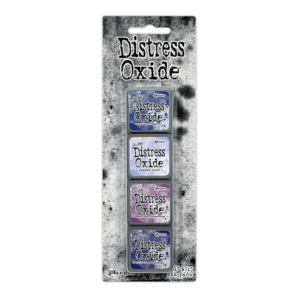 Packaged set of four Ranger Distress Oxide Mini Ink Pads from Kit 5 in Prize Ribbon, Shaded Lilac, Seedless Preserves and Villainous Potion, shown in original Tim Holtz packaging with grungy black-and-white background.
