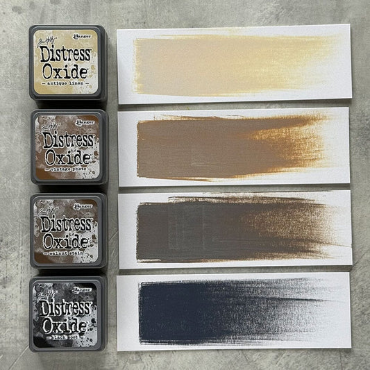 Four Ranger Distress Oxide ink pads from Kit 6 with swatched colours: Antique Linen, Vintage Photo, Walnut Stain and Black Soot, shown on white paper beside each labelled pad.
