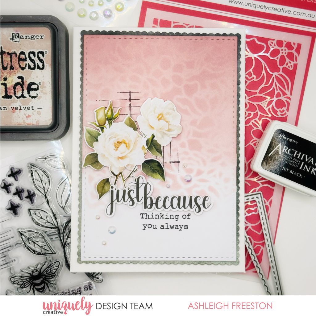 Handmade card by Ashleigh Freeston using Uniquely Creative Botanical Chronicles collection – features white roses, stitched border, and soft pink heart-patterned background. Sentiments “just because” and “Thinking of you always” offer gentle comfort, surrounded by crafting tools and floral embellishments.