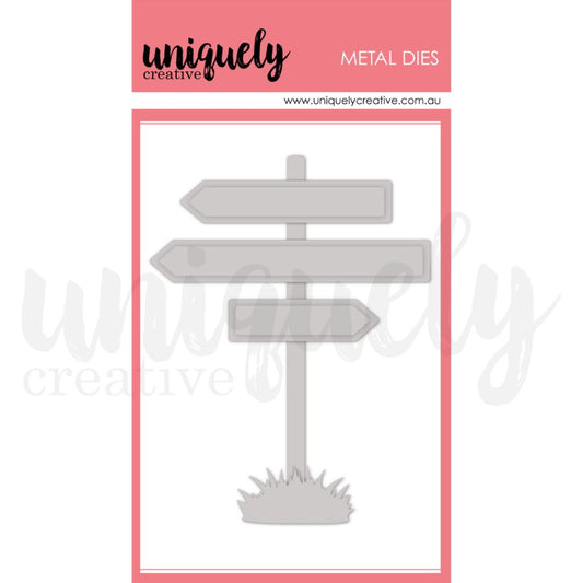 Uniquely Creative Beach Sign Metal Die showing signpost with grass base and three directional banner dies on pink branded packaging