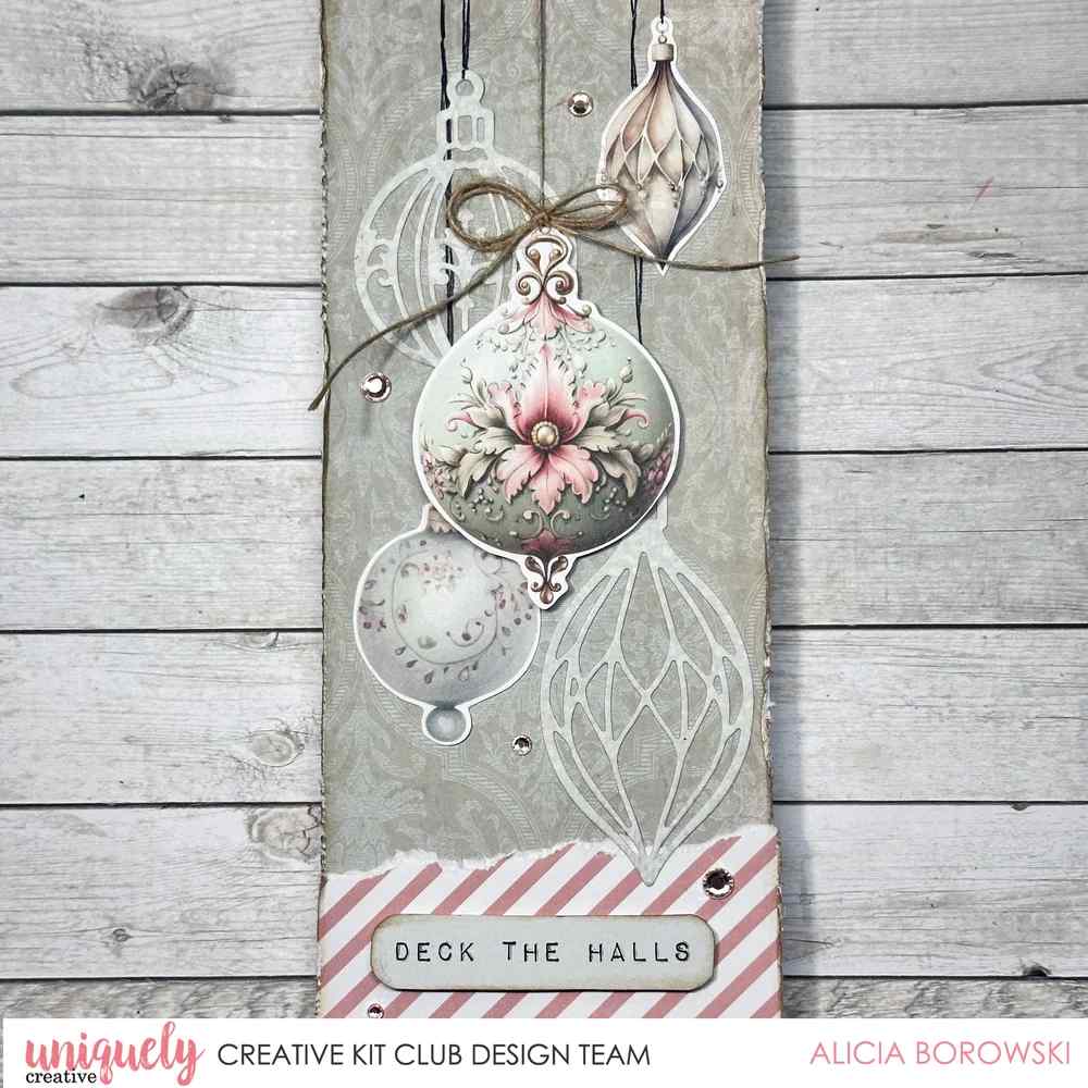 Christmas tag with layered bauble and finial die cuts, a floral ornament image and a Deck the Halls sentiment on a rustic wood background