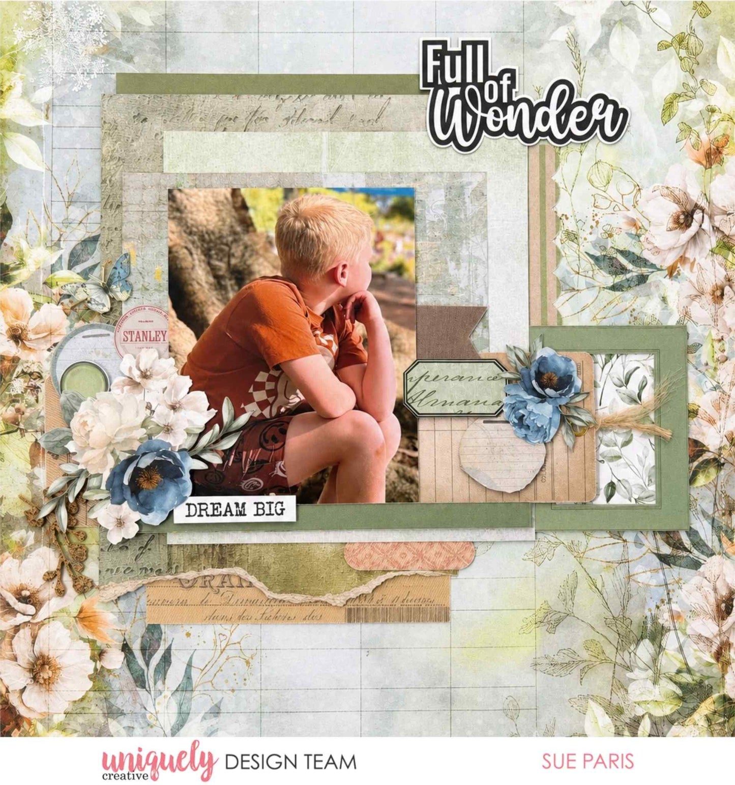 Scrapbook layout titled "Full of Wonder" with "Dream Big" sentiment featuring a photo of a boy sitting outdoors, surrounded by white and blue floral die-cuts on layered sage green and script patterned papers, made with Uniquely Creative Delighted Curiosities