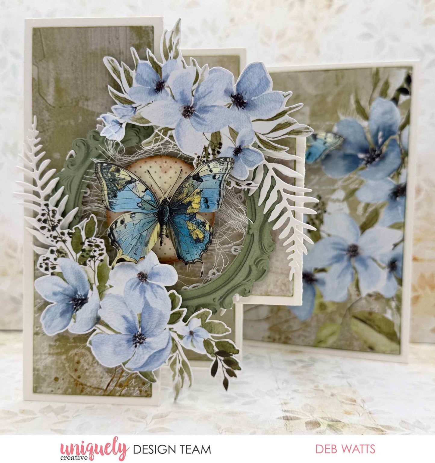 Handmade step card featuring die-cut blue florals and a detailed butterfly embellishment, made with Uniquely Creative Delighted Curiosities papers and Creative Cuts