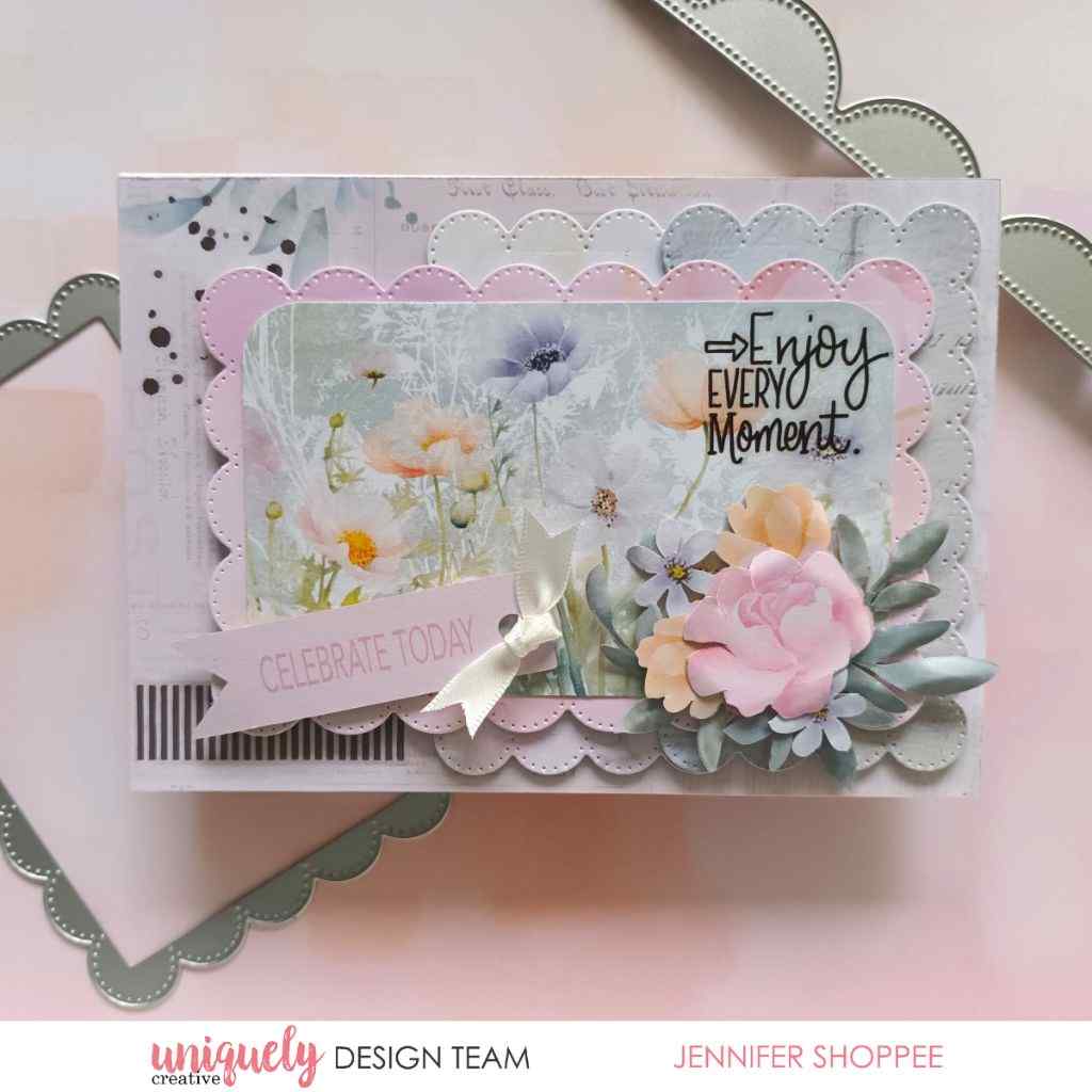 Handmade card sample featuring a floral paper panel, layered scalloped borders, a white bow, floral embellishments and “Enjoy Every Moment” lettering.⠋
