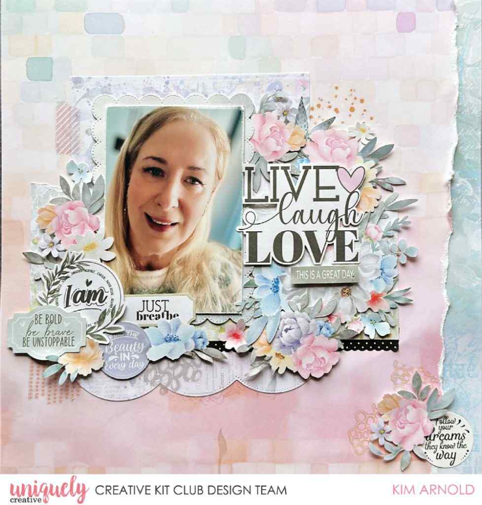 A scrapbook layout design featuring a layered paper collage from the Heart & Soul Collection with a central photo of a smiling blonde woman, surrounded by pastel pink, blue, and white floral elements, layered papers, and decorative text including 'LIVE laugh LOVE' and 'Just breathe'.