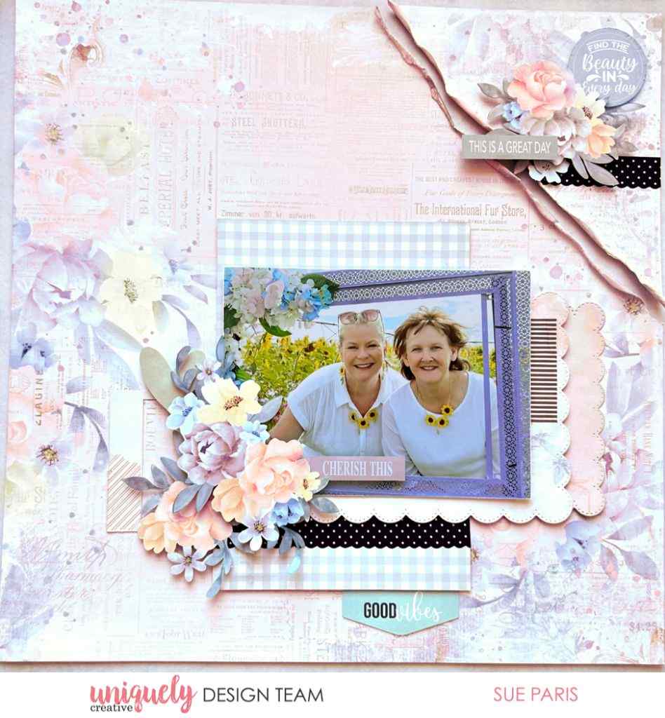 Scrapbook layout sample with a photo of two women, layered blue and floral papers, floral embellishments and a “Cherish This” title.