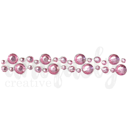 Close-up of pink rhinestone tape showing alternating large and small faceted gems creating a sparkling dimensional border for paper crafts