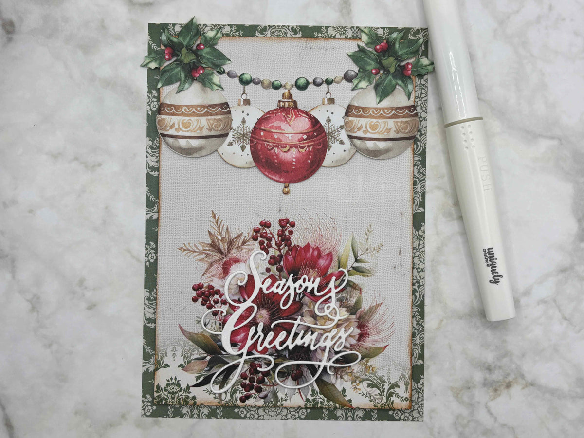 Christmas card featuring the Season's Greetings die with hanging baubles and a floral bouquet