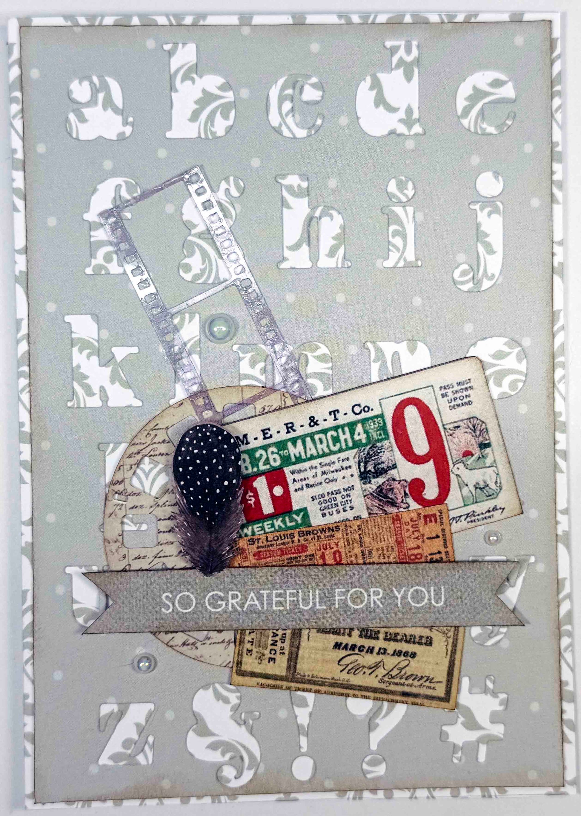 Handmade card using Uniquely Creative Serif Lowercase Alpha Die with white dimensional letters on grey background, vintage ephemera, black feather and So Grateful For You sentiment