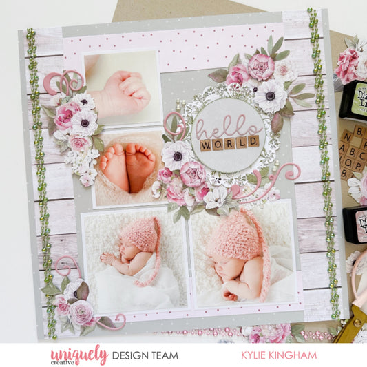 12x12 newborn baby scrapbook layout using Uniquely Creative Whispers of Wisdom collection featuring hello world sentiment with alphabet tiles, watercolour florals in blush pink, white wood grain paper, pink polka dots, and decorative doily frame embellishment