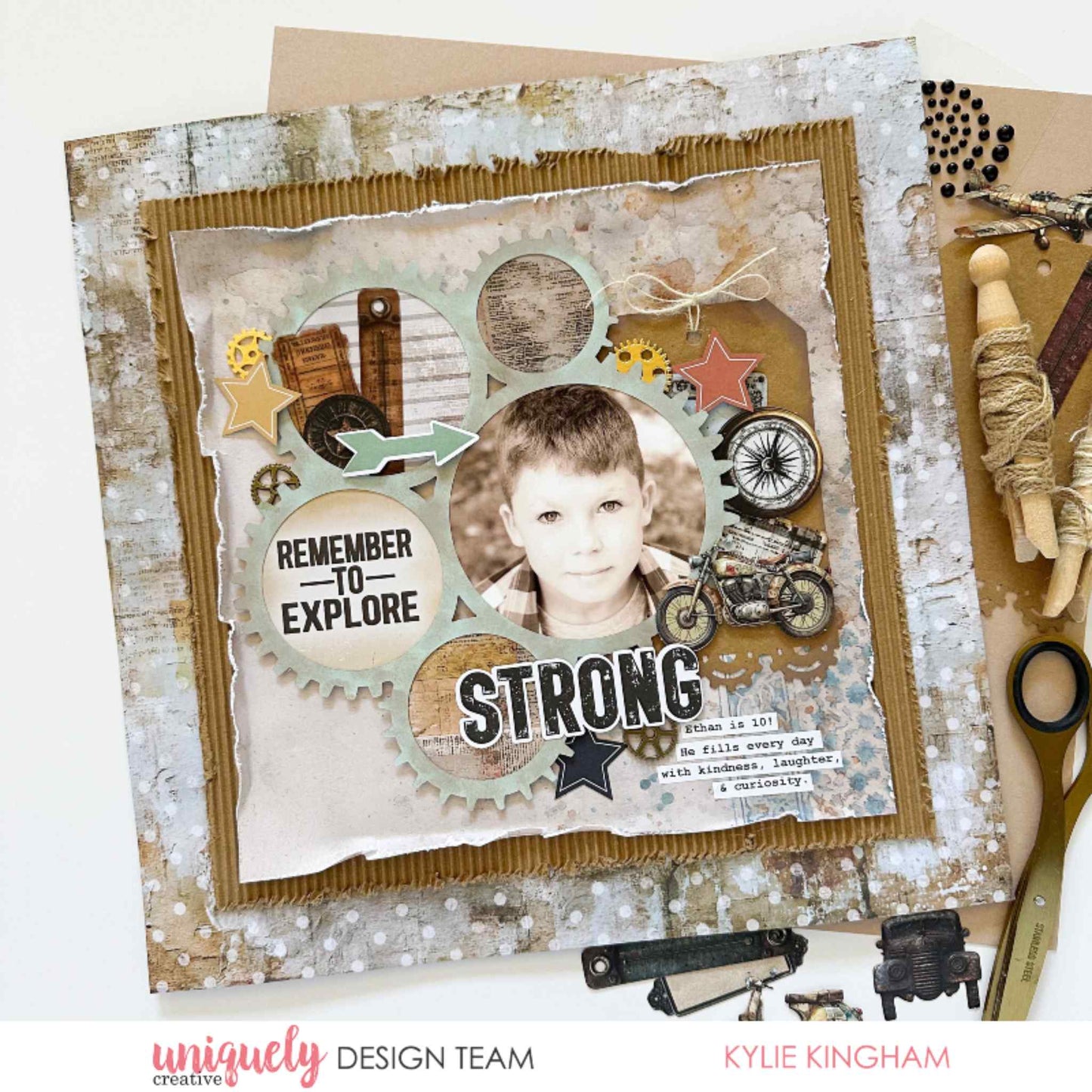 Scrapbook layout using Uniquely Creative Wings and Wheels paper, featuring boy's portrait in gear-shaped frames with Strong title, Remember to Explore sentiment, motorcycle and compass embellishments