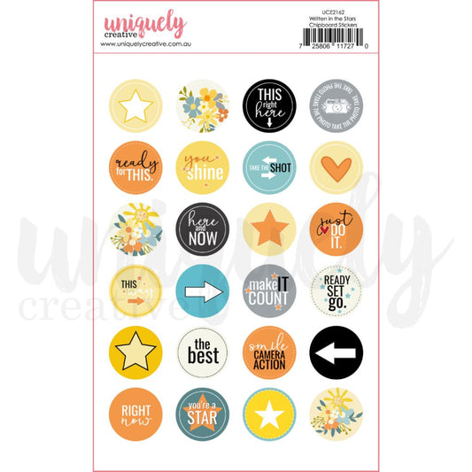 Uniquely Creative Written in the Stars Chipboard Stickers showing 24 circular stickers with sentiments including This Right Here, You Shine, Here and Now, Make It Count, You're a Star, plus star icons, florals, hearts and arrows in yellow, orange, teal and grey